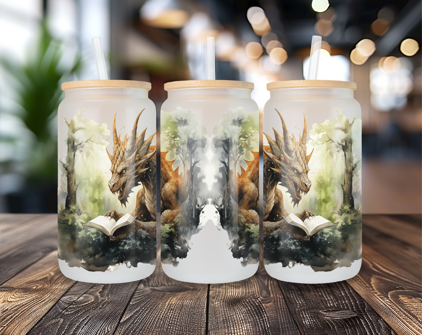 Three different perspectives of a frosted glass can featuring a detailed brown-scaled dragon reading a book in a mystical forest. Each glass has a bamboo lid and a clear straw, displayed on a wooden table with a blurred indoor background.